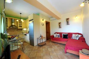 Villa Casa Bianca Orange Apartment في جايوس: غرفة معيشة مع أريكة حمراء ومطبخ