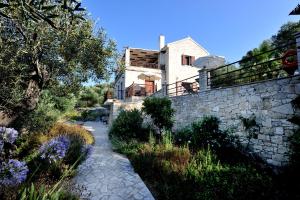 una casa con una pared de piedra y un camino de piedra en Villa Casa Bianca Purple Apartment, en Bogdanátika