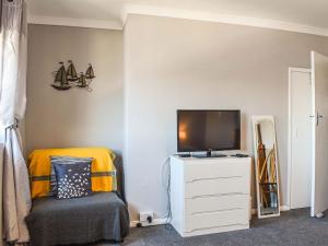 a bedroom with a tv on a dresser with a chair at Helens View in Torpoint