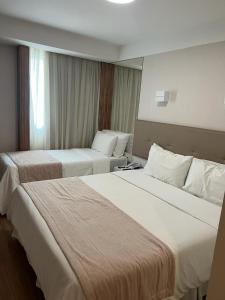 ein Hotelzimmer mit 2 Betten und einem Fenster in der Unterkunft Linhares Design Hotel in Linhares