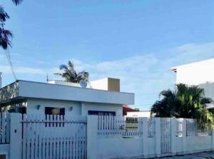 una cerca blanca frente a una casa blanca en Residencial Casa da Vila apto 3, en Imbituba