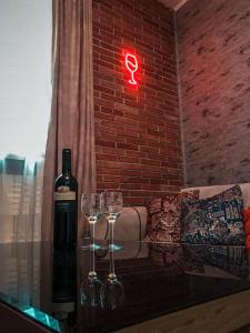 提比里斯的住宿－Sioni Apartment，砖墙旁的一瓶葡萄酒和两杯酒