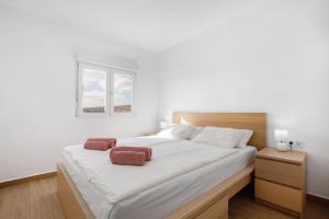um quarto com uma grande cama branca e 2 toalhas castanhas em Casa Aliana em Puerto del Rosario