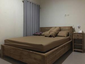 1 cama con marco de madera en un dormitorio en Juicezzy Home Fully Furnished 3 BR Guest House, en Singaraja