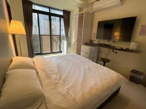 內埔鄉的住宿－愛瑪仕民宿，卧室设有一张白色大床和一扇窗户。