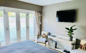 a bedroom with a bed and a tv on the wall at The Thorpe Guesthouse in Huntingdon