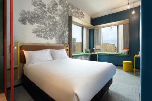 a bedroom with a large white bed and two windows at ibis Styles Copenhagen Orestad in Copenhagen