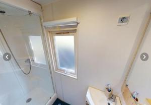 uma casa de banho com um chuveiro, um lavatório e uma janela em Campasun Camping de l'Aigle em Aiguines