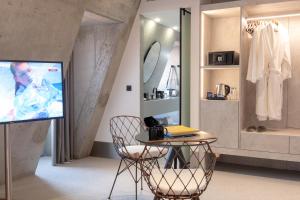 a living room with a tv and a table with a chair at Hotel Cajú in Funchal