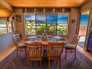 a dining room with a table and chairs and a large window at Aorere House - Collingwood Holiday Home in Collingwood