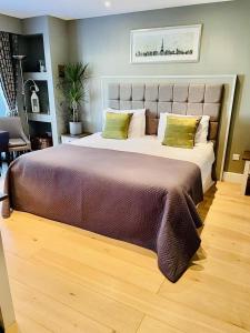 1 cama grande con 2 almohadas verdes encima en The Thorpe Guesthouse, en Huntingdon
