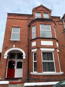 a red brick building with a red door and windows at ISUITES in Newcastle under Lyme