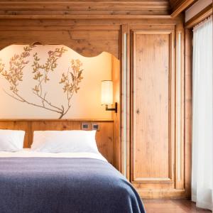 a bedroom with a bed with a large headboard at Faloria Mountain Spa Resort in Cortina dʼAmpezzo