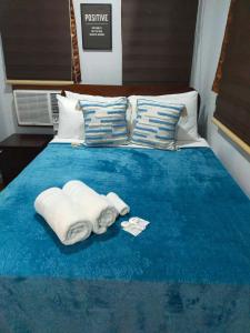 een bed met twee handdoeken op een blauw bed bij Point Gate Inn in Bacolod