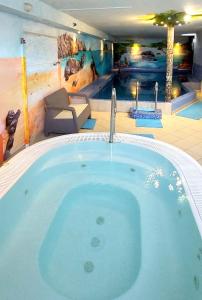 米茲多洛傑的住宿－庫拉布旅館，一个带游泳池的房间里的一个大型热水浴缸