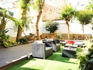eine Terrasse mit Korbstühlen und Tischen auf Gras in der Unterkunft Portrait Boutique Guesthouse in Valencia