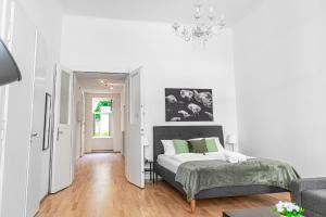 Habitación blanca con cama y lámpara de araña. en Modern 2BR Apt. Perfect for Long and Short Stays en Viena