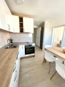 a kitchen with white cabinets and a wooden table at Ivana apartman 2 in Lovište