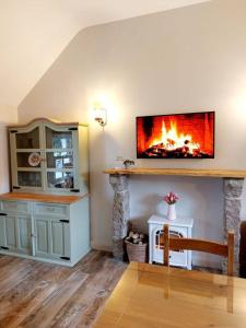 a living room with a fireplace with a tv on the wall at Wildthorn Cottage in Moyad
