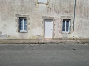 un edificio con una porta bianca e due finestre di Appartement centre ville proche citadelle a Le Château-dʼOléron