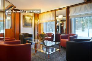 ミュンヘンにあるアンバサダー パークホテルの赤い椅子とガラスのテーブルが備わる待合室