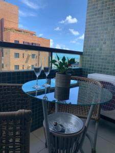 a table with two wine glasses and a potted plant on a balcony at Tambaú Beach Paradise in João Pessoa