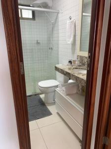 uma casa de banho com um WC, um lavatório e um espelho. em Tambaú Beach Paradise em João Pessoa