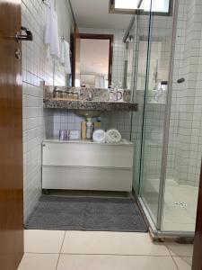 a bathroom with a glass shower and a sink at Tambaú Beach Paradise in João Pessoa