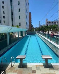 a swimming pool with two benches in a building at Tambaú Beach Paradise in João Pessoa