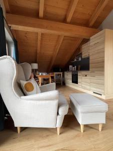 a living room with a white chair and a table at Das Bergquartier - Ferienwohnung Mühlberg in Oberau