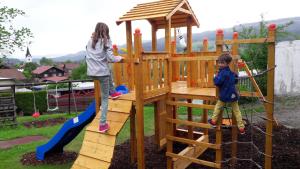two young children playing on a wooden playground at Leihwohnwagen Camping-Aach in Oberstaufen