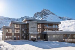 a building in the snow with a mountain in the background at Résidence Ynycio in Tignes
