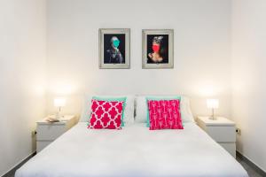 una camera da letto con un grande letto bianco con due immagini sul muro di Ferdinando Art House by Wonderful Italy a Napoli