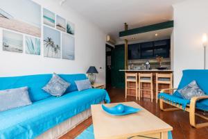 een woonkamer met een blauwe bank en een keuken bij Parque dos Reis Apartment in Monte Gordo