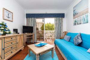 a living room with a blue couch and a tv at Parque dos Reis Apartment in Monte Gordo