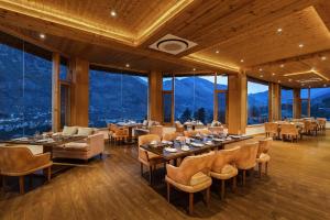 a restaurant with tables and chairs and large windows at Baragarh Resort & Spa, Manali- IHCL SeleQtions in Manāli