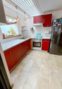 a kitchen with red cabinets and a stainless steel refrigerator at Calme et apaisant in La Saline les Bains