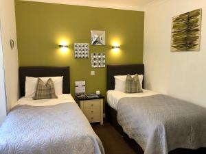 2 łóżka w pokoju z zielonymi ścianami w obiekcie Distant Hills Guest House w mieście Spean Bridge