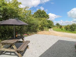 a picnic table with an umbrella next to a dirt road at Bailey Cottage in Truro