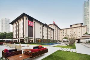 a hotel with benches and tables in a courtyard at Ibis Bangkok Riverside in Bangkok