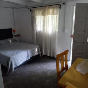 1 dormitorio con cama, mesa y ventana en Villa Cura Brochero - La Moradita de VIlla Los Sauces en Villa Cura Brochero