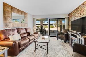 a living room with a brown leather couch and a tv at Tranquil Trail #3 in Carefree