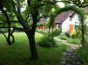 una casa con un árbol delante de un patio en La Chaumière - petit-déjeuner inclus à 15 min de Versailles en Jouars-Pontchartrain