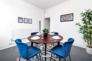 jadalnia z drewnianym stołem i niebieskimi krzesłami w obiekcie Chorlton House by Truestays - NEW 2 Bedroom House in Stoke-on-Trent w mieście Hanley