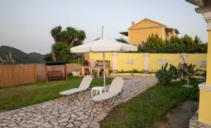 een patio met 2 stoelen en een parasol bij Maria’s House Arillas Corfu in Arillas