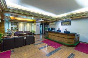 a lobby with a bar with two people sitting at it at Sel Nibash Hotel & Serviced Apartments in Dhaka