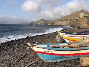 twee boten op een rotsachtig strand naast de oceaan bij Casa Fabrice in Ribeira da Prata