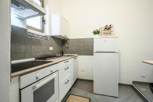 cocina blanca con fregadero y nevera en Attico con travi a vista - Free WiFi & Private Parking, en Massa Lombarda