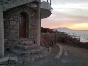 een stenen gebouw met een deur en een trap naast de oceaan bij Casa Fabrice in Ribeira da Prata