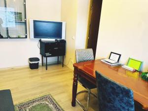 a room with a desk with a television and a table with chairs at 3min walk to Vilnius business center in Vilnius